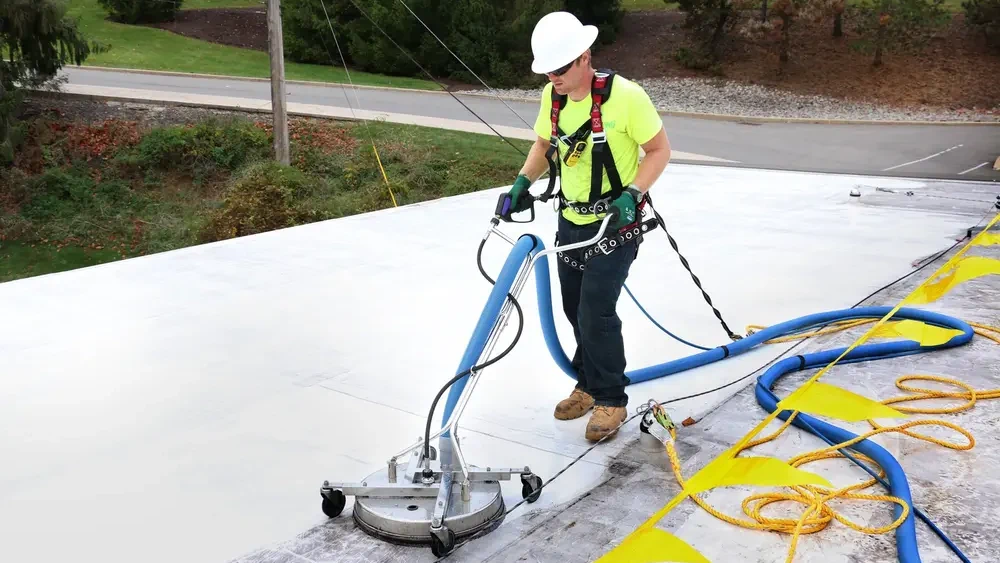 Construction worker using Tremco’s RoofTec system to clean rooftop  